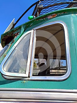 Close up of the open side window of an old green rusty vintage bus