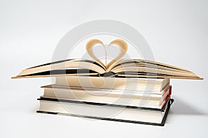 Close up of opened book with heart shaped from two pages, isolated on white background.