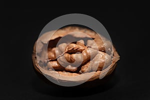 Close-up of an opened walnut. The nut kernel is still in the shell. The background is dark