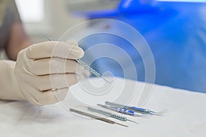 Close-up of an ophthalmologist doctor holding instruments for microscopic eye surgery in his hand over a sterile table