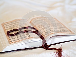 Close up oppened the holy Quran book with rosary on a white background. Morning prayer at Hijri New Year, August 30
