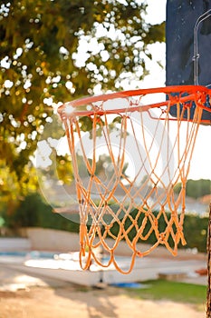 Close-up of an orange basketball net in an outdoor setting next to a pool