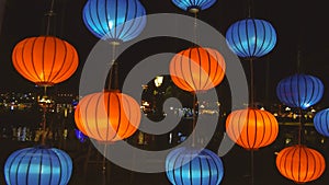 CLOSE UP: Orange and blue oriental lanterns shine bright during a festive night.