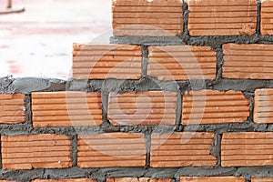 A close up of orange bricks mason We are building the walls of the house, designing the arrangement of bricks to create the walls