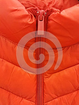 Close-up on orange puffer jacket texture with a zipper and a runner close-up photo