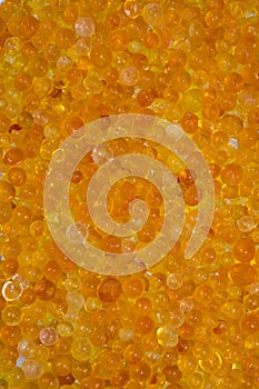 Close up of orange silica gel dessicant. Golden translucent beads with shiny light