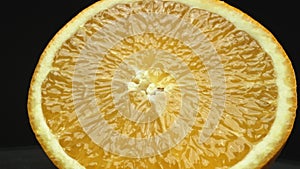 Close up of an orange slice, placed against isolated black backdrop. Comestible.