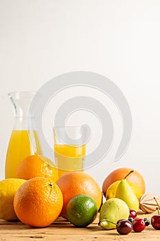 Close up of oranges, grapefruits, cherries and pears on wooden table with bottle and glass of orange juice