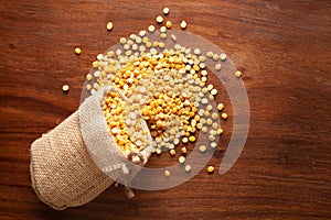 Close-up of Organic Bengal Gram Cicer arietinum or split yellow chana dal spilled out from a laying jute bag over wooden
