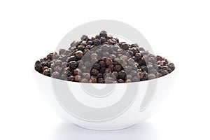 Close-up of Organic Black pepper Piper nigrum on a ceramic white bowl. Pile of Indian Aromatic Spice