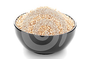 Close-Up of organic broken wheat dalia or daliya  roasted  in black ceramic bowl over white background