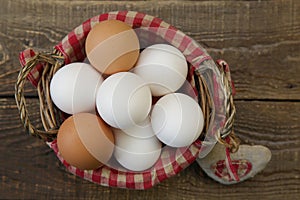 Close-up organic eggs in a basket with a decorated checkered napkin and a heart made of linen fabric on a wooden rustic background