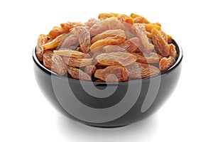 Close-up of organic golden long size raisins dry grapes in a black ceramic bowl over white background