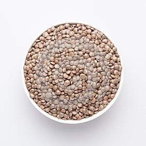 Close up of Organic masoor dal Lens culinaris or whole brown  dal on a ceramic white bowl.