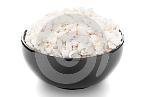 Close-up of organic  puffed / roasted rice kheel or murmura  in a black ceramic bowl over white background