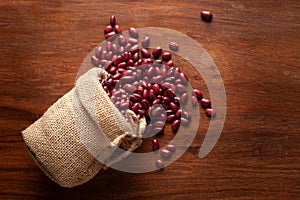 Close-up of Organic Rajma,  Laal Lobia  or red kidney beans dal spilled out from a laying jute bag over wooden brown background