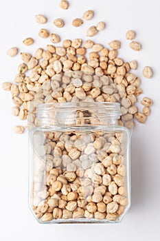 Close up of Organic small chhole chana or Kabuli chana Cicer arietinum or whole white Bengal gram dal spilled and in a glass jar