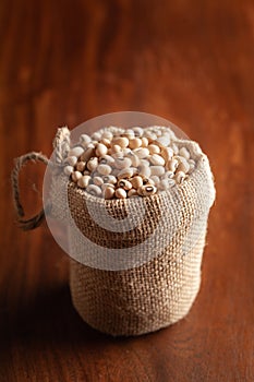Close-up of Organic soybean,  Glycine max  or soya bean dal in a standing jute bag over wooden brown background