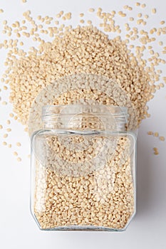 Close up of Organic split polished white urad dal Vigna mungo spilled and in a glass jar. photo