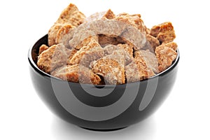 Close-Up of organic sugarcane jaggery piece in black ceramic bowl over white background