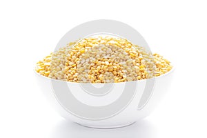 Close up of Organic yellow Gram Vigna radiata or split yellow moong dal inside a ceramic white bowl. Top view