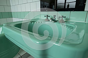 Close up of original green vintage retro 1930s deco wash basin and stainless steel taps.