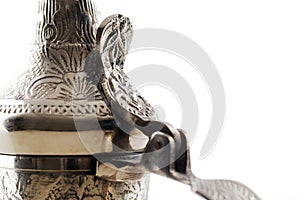 A close up of an ornate dallah, the metal pot for making Arabic coffee