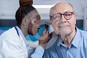 Close up of otology specialist examining senior person using otoscope photo