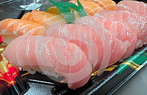 Close up of Otoro sushi and salmon sushi on black plastic plate, ready to eat from Japanese supermarket