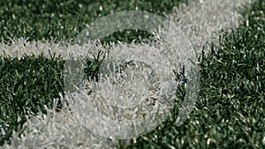 Close up of the out of bounds line on a turf football field.