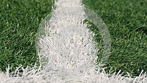 Close up of the out of bounds line on a turf football field.