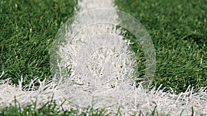 Close up of the out of bounds line on a turf football field.