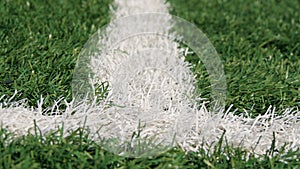 Close up of the out of bounds line on a turf football field.