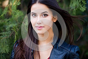 Close up outdoor portrait of young beautiful brunette woman with green eyes and long healthy hair.