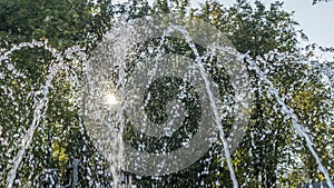 Close-up outdoor view of a public fountain with many small water jets. Public park background.