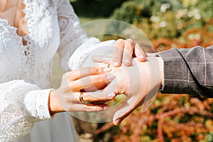 Close-up of an outdoor wedding ceremony, bride puts ring on groom's hand, newlyweds exchange rings.