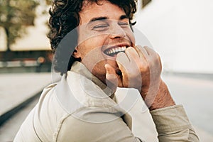 Close-up outdoors portrait of handsome happy young man smiling broadly posing for advertisement, smiling and looking at the camera