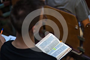 Close-up over-the-shoulder view of a young man holding an open bible