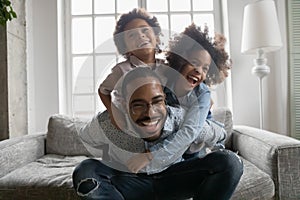 Close up overjoyed African American man piggy backing kids