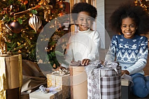 Close up overjoyed African American sister and brother unpacking gifts