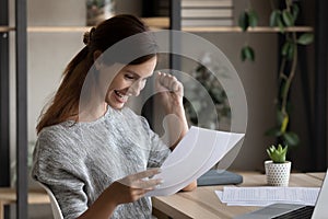 Close up overjoyed woman reading good news, holding letter