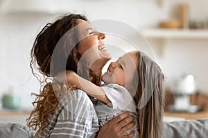 Close up overjoyed young mother and daughter hugging and laughing