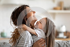 Close up overjoyed young mother and daughter hugging and laughing photo