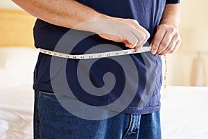 Close Up Of Overweight Man Measuring Waist