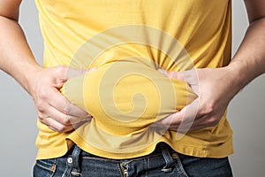 Close up of overweight man`s hand holding his big belly