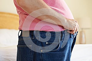 Close Up Of Overweight Man Trying To Fasten Trousers