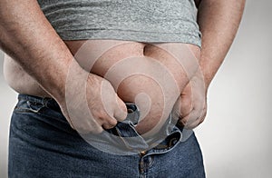 Close up of overweight man trying to wear small jeans