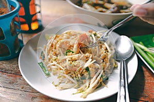 Close up pad thai noodle thai street food on wooden table with hand and fork