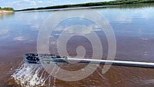 Close up of a paddle rowing upstream the river, on a traditional steel boat.