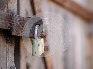 Close up of a padlock securing a rusty and weathered wooden door